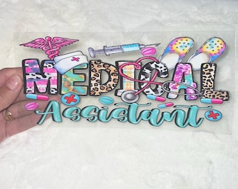 May include: A colorful vinyl decal with the words "Medical Assistant" in a whimsical font. The decal features a stethoscope, pills, a nurse's cap, and a pair of flip flops.