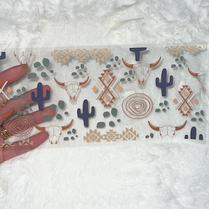 May include: A clear acrylic tray with a southwestern design featuring a repeating pattern of stylized skulls, cacti, and geometric shapes in shades of brown, orange, and blue.