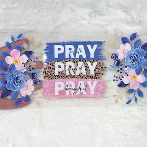May include: A clear plastic bookmark with a floral design and the text "Pray on it, Pray over it, Pray through it".