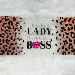 May include: A clear acrylic sign with a leopard print background and the text "act like a LADY. think like a BOSS." with a pink lipstick graphic.