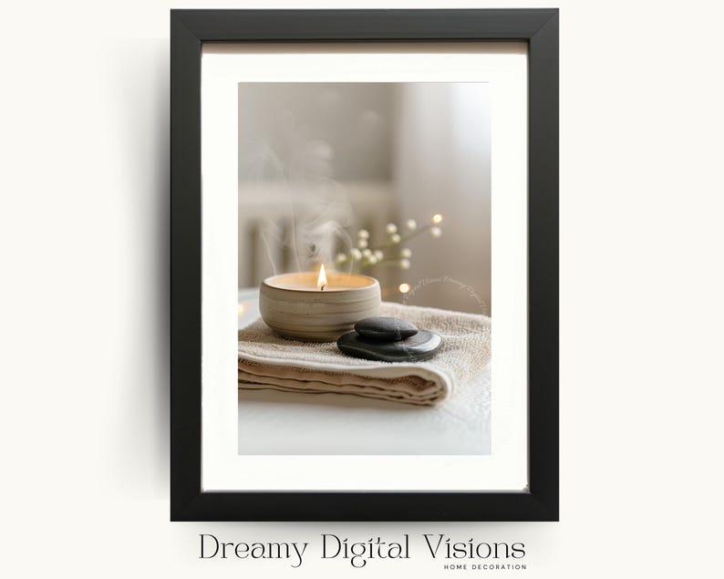 A framed digital artwork featuring a ceramic candle bowl with a warm flame and drifting smoke placed on folded neutral towels beside smooth black stones, presented in a minimalist black frame on a pale background to create a tranquil spa-inspired aesthetic ideal for calming bathroom wall art and zen home decor.