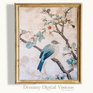 May include: Embroidered artwork in a gold frame featuring a blue bird perched on a branch with white and blue flowers. The background has a textured, off-white appearance. The artwork is labeled "Dreamy Digital Visions HOME DECORATION".