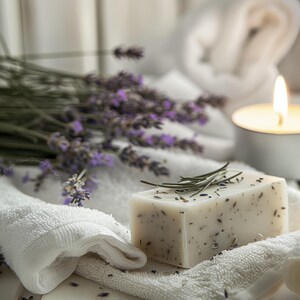 A close-up digital photograph of a handmade lavender soap resting on white textured towels with scattered lavender buds, fresh lavender stems and a softly glowing candle blurred in the background, captured in gentle natural light to create a soothing spa-like mood ideal for botanical bathroom decor and relaxing wall art.