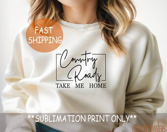 May include: Cream-colored sweatshirt with the text "Country Roads Take Me Home" in a black, handwritten-style font. The text is enclosed in a black rectangular border. The words "Sublimation Print Only" are at the bottom.
