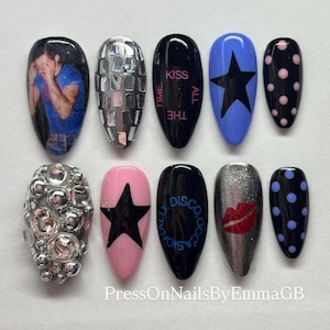 May include: A collection of ten press-on nails with diverse designs. The designs feature a photo, silver rhinestones, the text "Kiss All The Time", a black star on a blue background, pink polka dots, a silver studded nail, a black star on a pink background, the text "Disco Occasion", a red lip design, and blue polka dots.