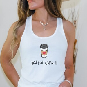 Puede incluir: Camiseta blanca de tirantes con un gráfico de una taza de café con un corazón y el texto "But first, Coffee!!!"