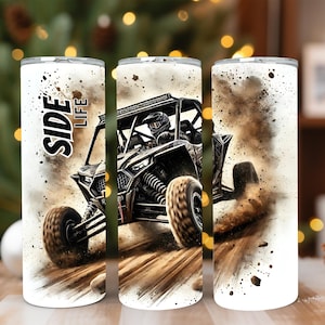 May include: White tumbler featuring a black off-road vehicle design with the text "SIDE LIFE". The design includes a driver in a helmet and goggles, kicking up dirt. The tumbler is cylindrical and suitable for hot or cold beverages.