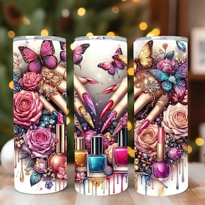 Puede incluir: Un vaso blanco con un diseño de arte de uñas, que incluye mariposas, rosas y botellas de esmalte de uñas. El diseño presenta uñas largas y cuidadas con varios colores y patrones, y detalles dorados. El tema es la belleza y la moda.