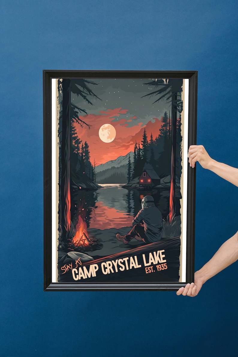 May include: A framed poster with a retro design featuring a dark silhouette of a person sitting by a campfire in front of a lake. The lake is surrounded by trees and mountains. The moon is full and red in the sky. The poster reads "Stay at Camp Crystal Lake Est. 1935".
