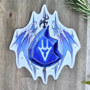 May include: A blue crystal with a white symbol inside, surrounded by two blue wings with white bones. The crystal is on a white background with a black spear behind it.