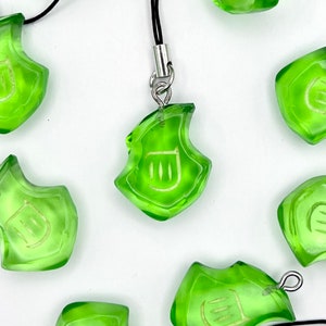 May include: A set of eight green glass charms with a white symbol on each. The charms are attached to black cords and have silver rings.