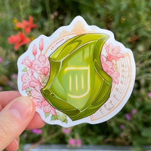 May include: A green and yellow sticker with a musical note design and a floral border. The sticker features the text "okii moon".