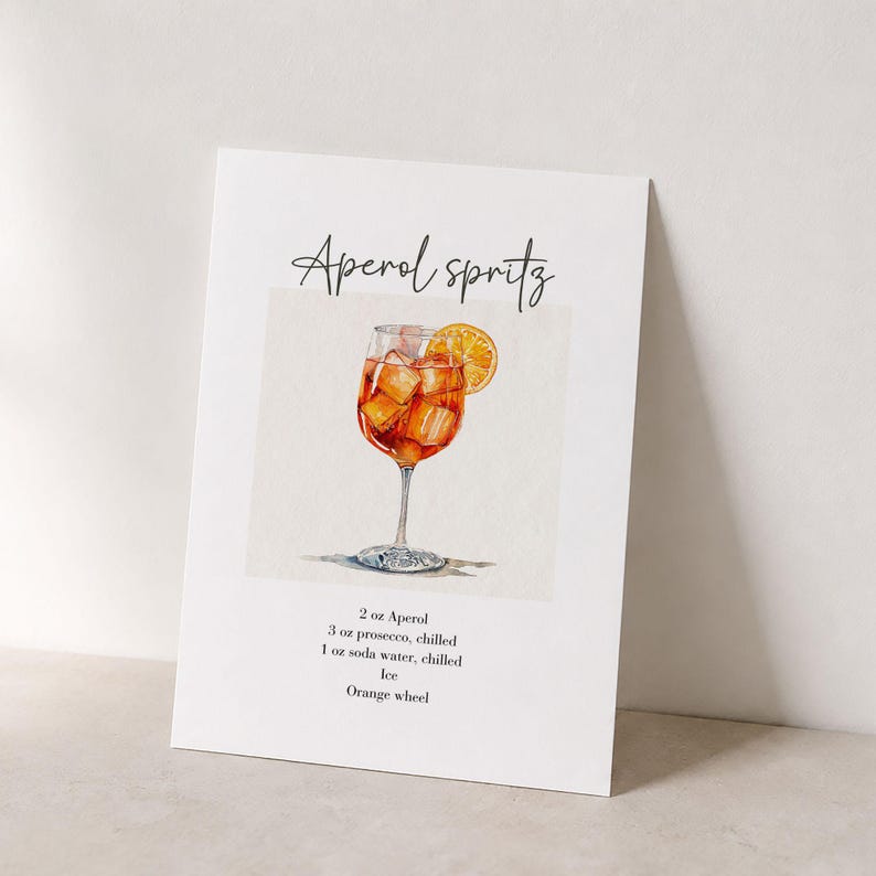Pode incluir: Uma impress&atilde;o retangular branca com uma ilustra&ccedil;&atilde;o em aguarela de um Aperol Spritz num copo com p&eacute;, gelo e uma fatia de laranja. O texto diz Aperol Spritz, 2 oz Aperol, 3 oz prosecco, 1 oz &aacute;gua com g&aacute;s, gelo, fatia de laranja.