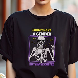 May include: Black t-shirt with a graphic of a skeleton holding a coffee cup. The text on the shirt reads "i don't have a gender but i have coffee".