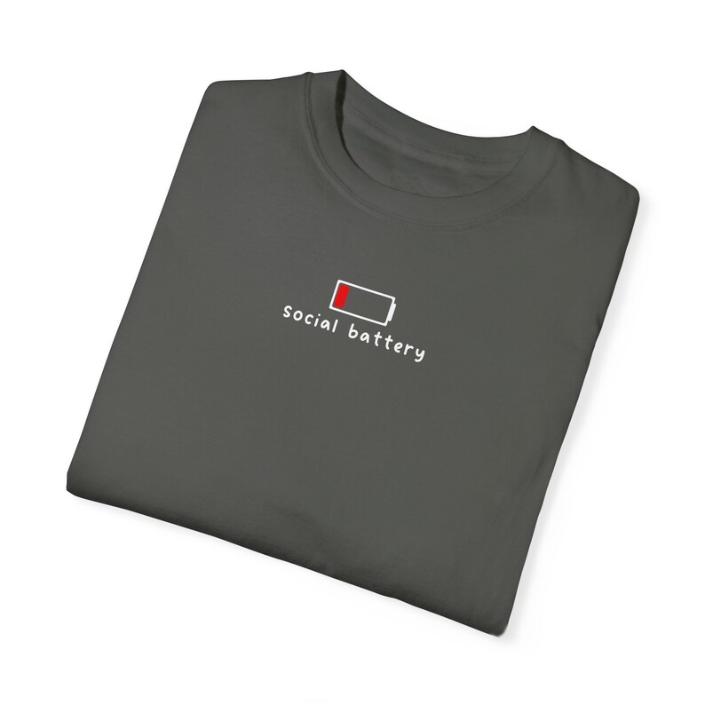 May include: A dark gray t-shirt with a white graphic of a low battery icon and the text "social battery".