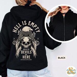 May include: Black zip-up hoodie with a graphic on the back featuring an eagle, skull, and the text "HELL IS EMPTY AND ALL THE DEVILS ARE HERE SHAKESPEARE". The hoodie has a drawstring hood and a front zipper.
