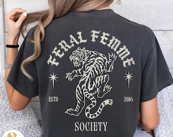 May include: A black t-shirt with a white graphic print of a tiger with the text "Feral Femme Society" and the dates "ESTD 2016" on the back.