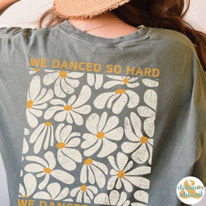 May include: A gray t-shirt with a white daisy print and the text "WE DANCED SO HARD" on the back.