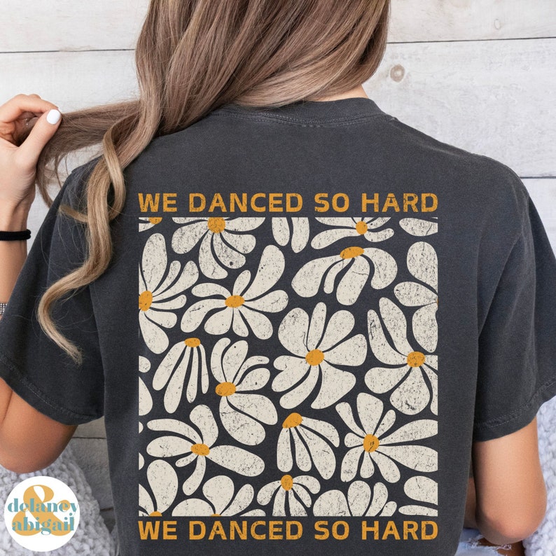 May include: A dark grey t-shirt with a white daisy print and the text "WE DANCED SO HARD" on the back.