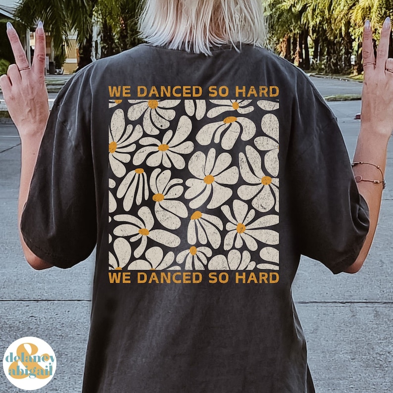 May include: A black t-shirt with a white daisy print and the text "We danced so hard" in yellow.