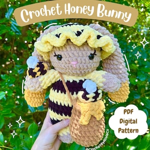 May include: A handmade crochet Honey Bunny plushie, with a yellow and black bee design. The bunny has long, floppy ears, a yellow ruffled headpiece, and a small honey pot purse. The text "Crochet Honey Bunny" is displayed above the plushie.