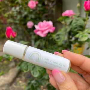 Könnte beinhalten: Eine weiße Rollflasche mit einem grün-weißen Etikett, auf dem "I AM Calm Kids My calming roller" steht. Das Etikett zeigt auch eine Regenbogengrafik.