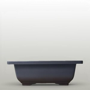 May include: A rectangular dark grey bonsai pot with a wide, flat rim and a smooth, matte finish. The container features a deep basin with slightly tapered sides and is supported by four small, integrated feet at the base for elevation.