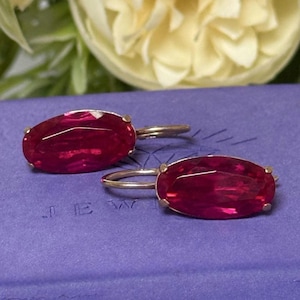 May include: A white ceramic mug with a black handle and the text "But First, Coffee" in a bold, black font. The mug is filled with a dark liquid, likely coffee, and sits on a light-colored surface.