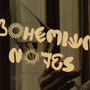 May include: A glass of wine is held up, with the words "Bohemian Notes" in a tan, stylized font. The background is a warm, muted brown with decorative sun and floral shapes.