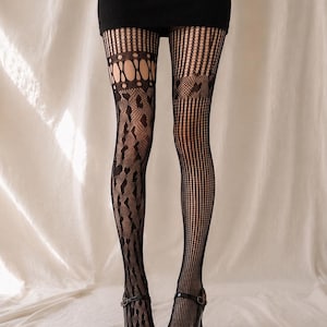 Può includere: Collant neri a fantasia caratterizzati da un complesso design traforato con strisce verticali, forme a rombo e ritagli circolari. Le calze sono abbinate a décolleté Mary Jane in vernice nera e a una minigonna nera a coste.