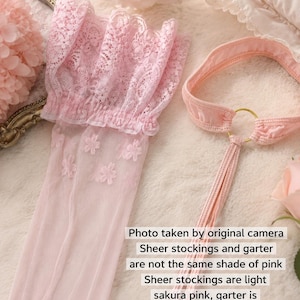 May include: A pair of light sakura pink sheer stockings featuring a floral lace cuff and a light nude pink garter belt with a gold-tone ring connector. The image includes text stating: Photo taken by original camera. Sheer stockings and garter are not the same shade of pink. Sheer stockings are light sakura pink, garter is light nude pink (designed to match like this).