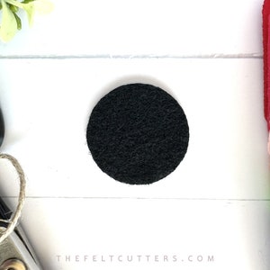 May include: A black felt circle, approximately 2 inches in diameter. The circle is on a white surface.