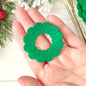 May include: A green felt wreath with a scalloped edge. The wreath is about 2 inches in diameter.