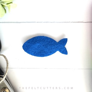 May include: A blue felt fish cutout. The fish is about 2 inches long and 1 inch wide. It is a simple design with a rounded body and a small tail fin.