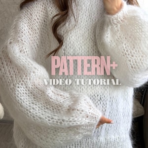 May include: A white, open-knit sweater with long, puffy sleeves. The sweater has a textured appearance and is made of a soft, fluffy material. The text "PATTERN + VIDEO TUTORIAL" is overlaid on the image in pink.