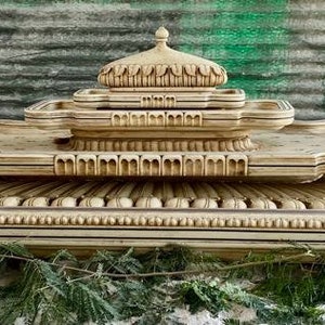 May include: A tiered fountain crafted from white stone, featuring intricate carvings and a layered design. The fountain has a dome-shaped top and a base with a scalloped edge.