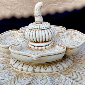 May include: White ceramic decorative centerpiece with a lotus flower design. The centerpiece features a central dome with a pointed top and three smaller bowls around the base.