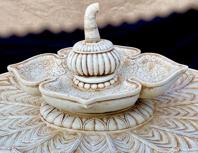 May include: White ceramic decorative centerpiece with a lotus flower design. The centerpiece features a central dome with a pointed top and three smaller bowls around the base.