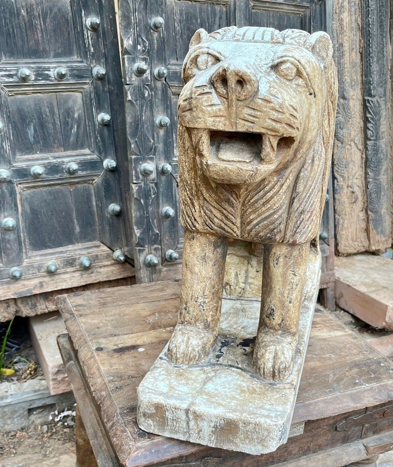Puede incluir: Una estatua de le&oacute;n de piedra tallada con un rostro y una melena detallados. La estatua est&aacute; de pie sobre una base rectangular y tiene un aspecto desgastado y antiguo.
