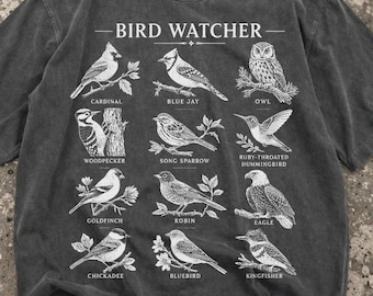 May include: Dark gray t-shirt featuring a detailed illustration of various bird species, including a cardinal, blue jay, and owl. The shirt is labeled "BIRD WATCHER" and includes the names of each bird. A comfortable, casual tee for bird enthusiasts.