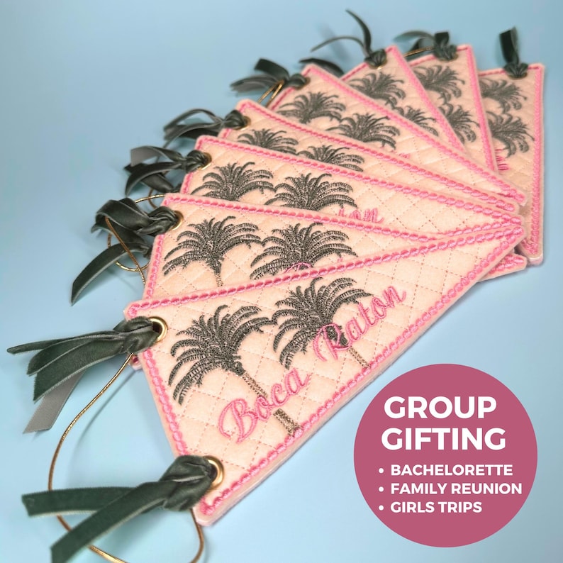 May include: A collection of quilted, diamond-patterned tags with a pink border and embroidered palm trees. The tags have the text "Boca Raton" in pink script and are adorned with green velvet ribbon and gold-colored metal rings. The image also includes a pink circle with the text "GROUP GIFTING".