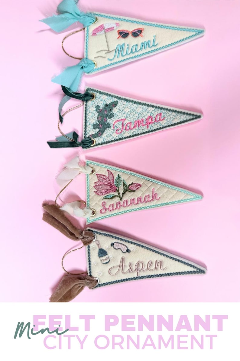 May include: Mini felt pennant city ornaments. Each triangular pennant features embroidered designs and city names like Miami, Tampa, Savannah, and Aspen. They have decorative trim and are adorned with ribbons.