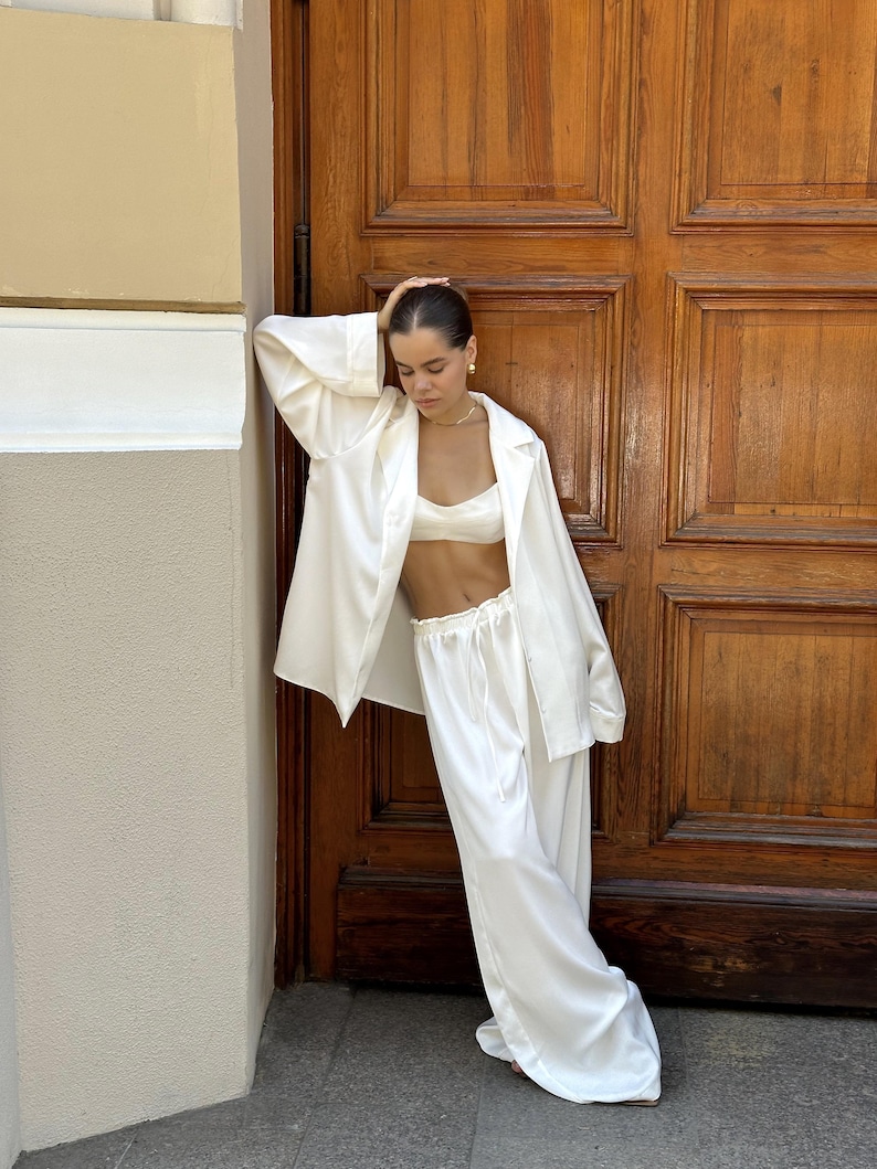 Bridal getting ready outfit satin bride pajama set with bralette pants and shirt. Elegant 3 piece bridal lounge set designed for bridal morning outfit and wedding day preparation. Soft satin bridal pajama set for bride getting ready photos, bridal prep outfit, comfortable and chic bride lounge set perfect for wedding morning, bridal preparation and special bridal moments.
