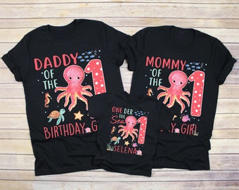May include: Black t-shirts with a red octopus and the text "Daddy of the 1st Birthday Girl", "Mommy of the 1st Birthday Girl", and "One Der the Sea Selena".