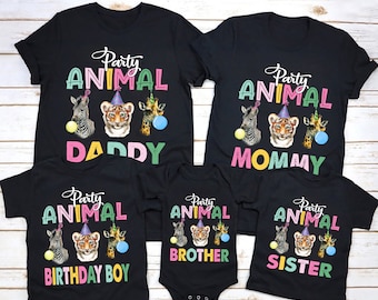 Könnte beinhalten: Ein Set aus fünf schwarzen T-Shirts mit einem Party-Tier-Motiv. Die Shirts zeigen einen Tiger, ein Zebra und eine Giraffe, die Partyhüte tragen. Der Text auf den Shirts lautet "Party Animal Daddy", "Party Animal Mommy", "Party Animal Birthday Boy", "Party Animal Brother" und "Party Animal Sister".