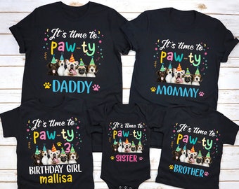 Puede incluir: ¡Es hora de la fiesta! Un conjunto de cinco camisetas negras con un tema de fiesta. Las camisetas presentan un grupo de perros con sombreros de fiesta y el texto "It's time to paw-ty". Las camisetas están etiquetadas como "Papá", "Mamá", "Niña de cumpleaños mallisa", "Hermana" y "Hermano".