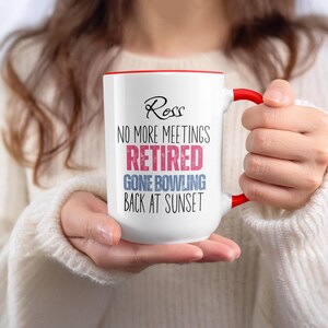 May include: White ceramic mug with a red interior and handle. The mug features the name "Ross" in script above the text "NO MORE MEETINGS RETIRED GONE BOWLING BACK AT SUNSET" in a mix of fonts and colors.