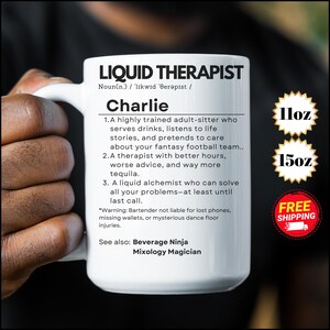 May include: White ceramic mug with a black outline and the text "Liquid Therapist" and "Charlie" in black. The mug also has the text "11oz" and "15oz" in black with yellow starbursts. The text "Free Shipping" is in white with a red starburst.