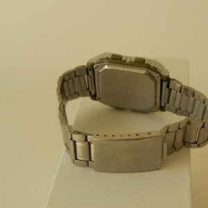 May include: A silver digital wristwatch with a square face and a metal band.