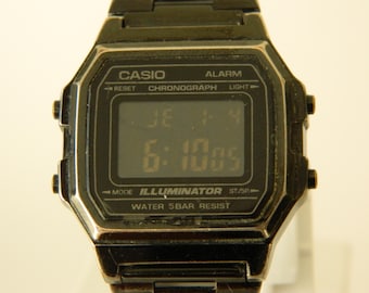 May include: A black Casio digital watch with a silver band. The watch face displays the time, 6:1005, and has buttons for alarm, chronograph, light, mode, and start/stop. The watch is water resistant to 5 bars.